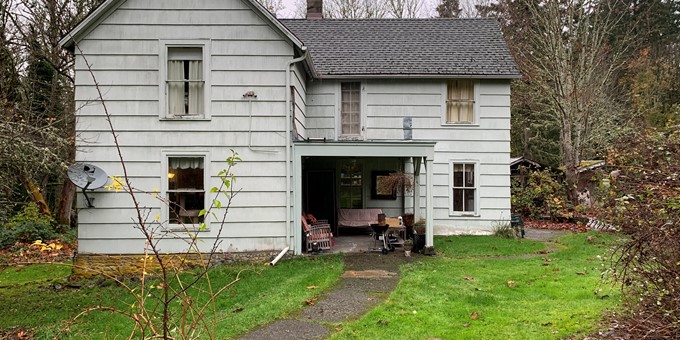 Old white two-story house on Parker Property in Sammamish with attached carport that will be demolished.